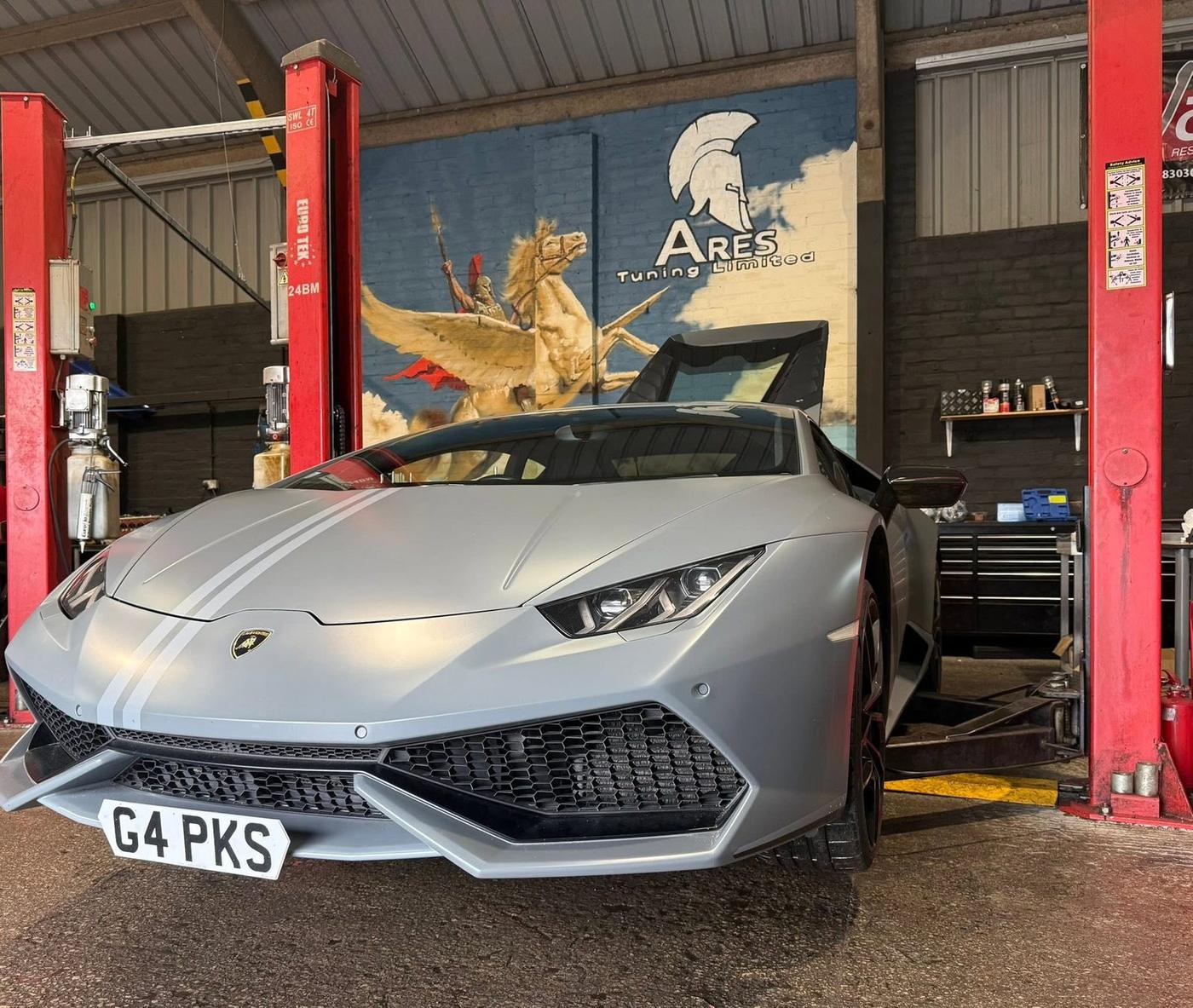 A Lamborghini Huracan in the ARES Tuning workshop, beneath the ARES mural